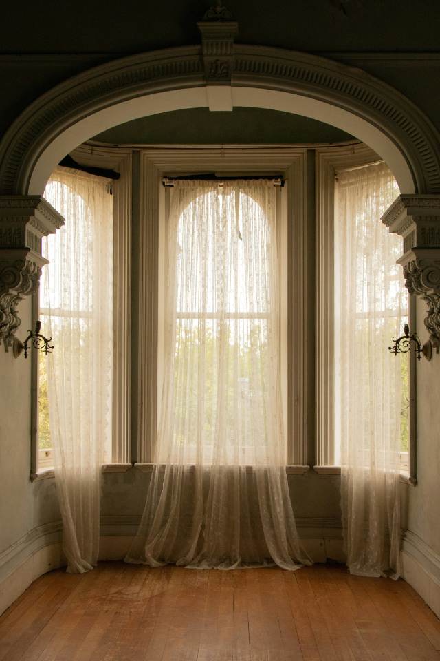 Tuscan inspired arch with details and large windows with sheer drapes